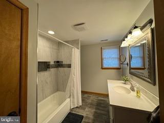 bathroom with shower / bath combo with shower curtain and vanity