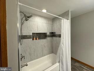 bathroom featuring wood-type flooring and shower / bath combo with shower curtain