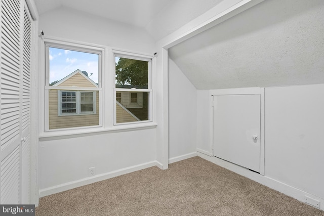 bonus room featuring light colored carpet, vaulted ceiling, and a textured ceiling