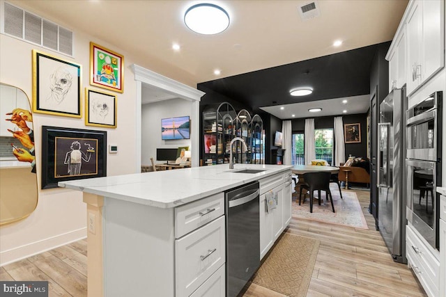 kitchen with sink, white cabinetry, an island with sink, and light hardwood / wood-style flooring