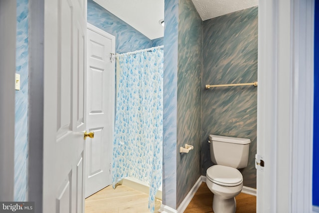 bathroom featuring hardwood / wood-style flooring, a textured ceiling, a shower with curtain, and toilet