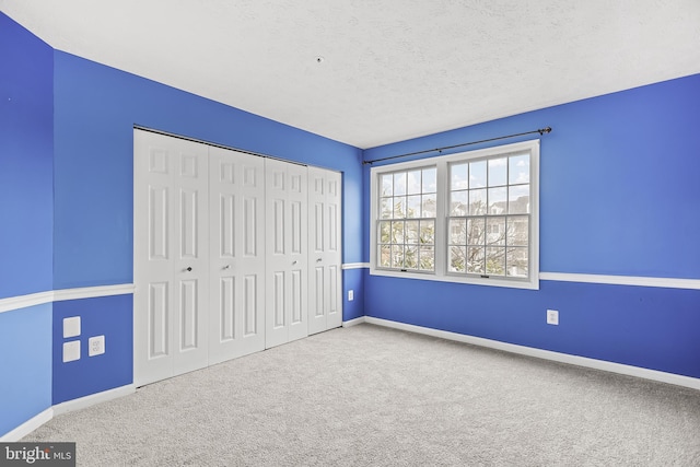 unfurnished bedroom with carpet floors, a closet, and a textured ceiling