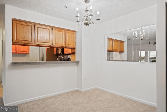 kitchen featuring decorative light fixtures, stainless steel refrigerator, kitchen peninsula, a notable chandelier, and light colored carpet