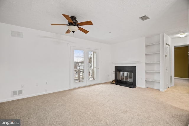 unfurnished living room featuring light carpet, ceiling fan, and a textured ceiling