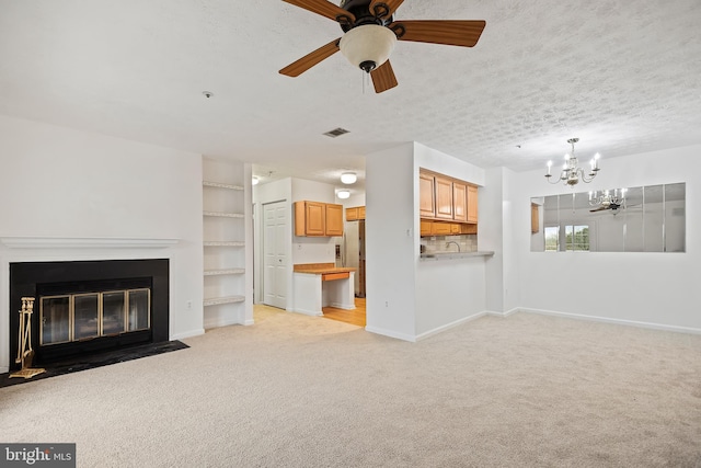 unfurnished living room with ceiling fan with notable chandelier, light carpet, and a textured ceiling