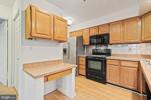 kitchen with tasteful backsplash, black appliances, light hardwood / wood-style floors, and a textured ceiling