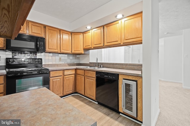 kitchen featuring wine cooler, sink, tasteful backsplash, a textured ceiling, and black appliances