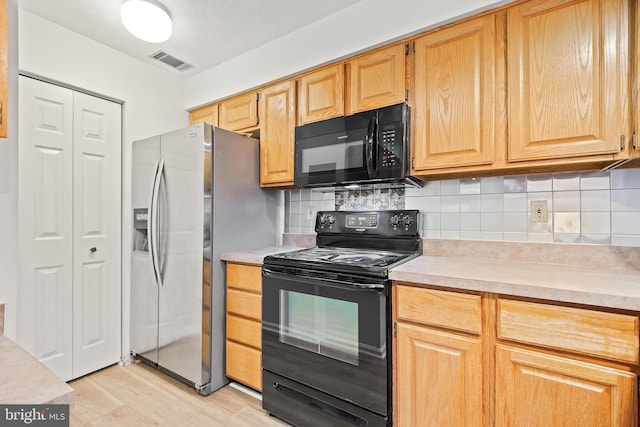 kitchen with backsplash, light wood-type flooring, and black appliances