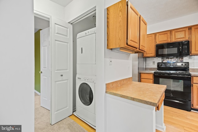 kitchen featuring stacked washer and clothes dryer, light wood-type flooring, decorative backsplash, and black appliances