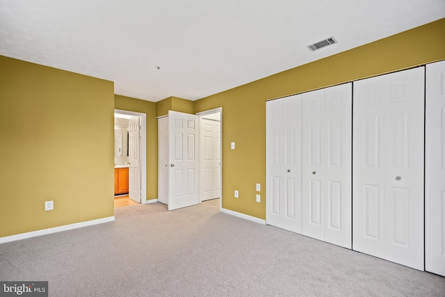 unfurnished bedroom featuring light carpet and ensuite bathroom