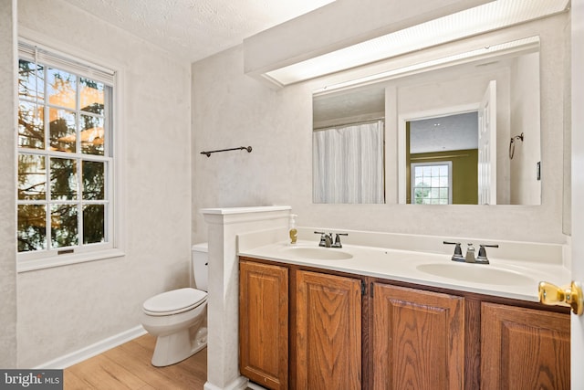 bathroom with vanity, toilet, wood-type flooring, and a textured ceiling