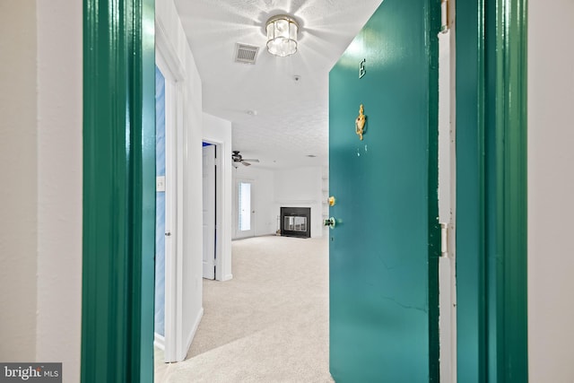 hallway featuring light carpet and a textured ceiling