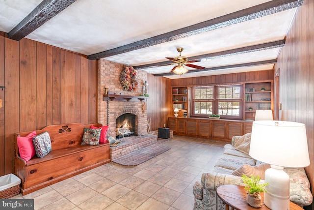 tiled living room with beam ceiling, a fireplace, wood walls, and built in features