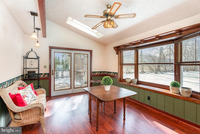 interior space with vaulted ceiling with skylight, ceiling fan, wood-type flooring, and a textured ceiling