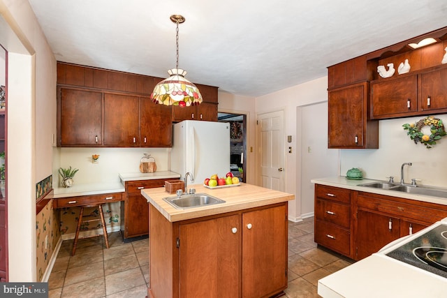 kitchen featuring a center island with sink, decorative light fixtures, white fridge, and sink