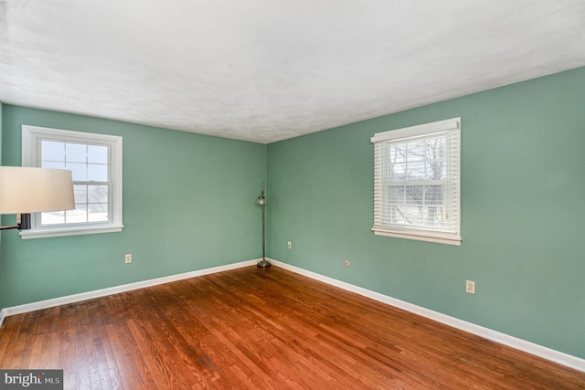 spare room with dark hardwood / wood-style flooring and a healthy amount of sunlight