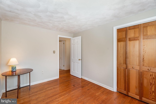 bedroom featuring wood-type flooring, a textured ceiling, and a closet