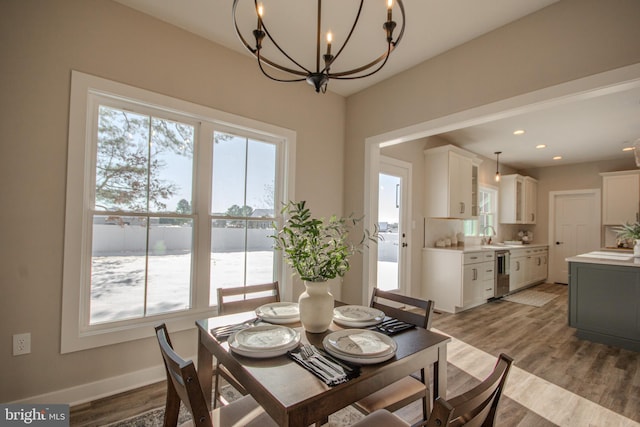 dining space featuring light wood-type flooring, an inviting chandelier, and sink