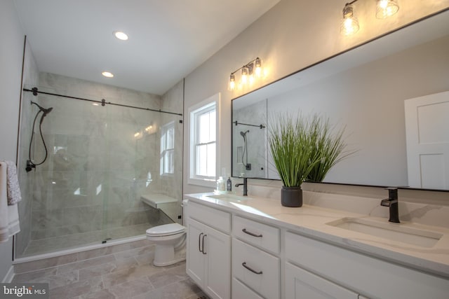 bathroom with a tile shower, vanity, and toilet