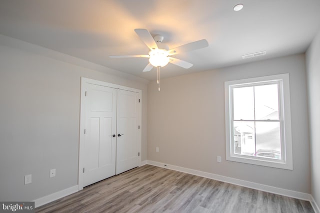 unfurnished bedroom featuring a closet, light hardwood / wood-style flooring, and ceiling fan