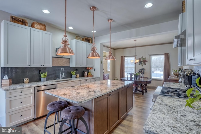 kitchen featuring sink, a center island, white cabinetry, stainless steel appliances, and hanging light fixtures