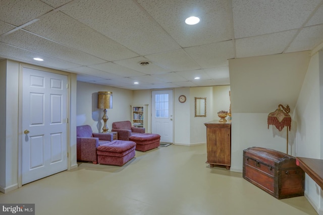 sitting room with a paneled ceiling and concrete floors