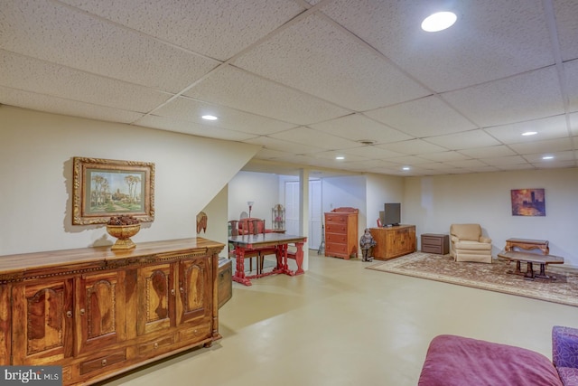 living area with a drop ceiling and concrete flooring