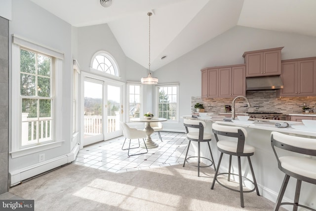 kitchen featuring a healthy amount of sunlight, decorative backsplash, hanging light fixtures, and a baseboard radiator