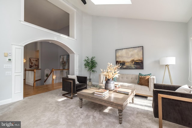 carpeted living room featuring high vaulted ceiling and a skylight