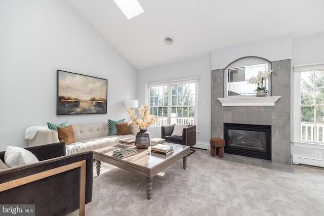 living room with a baseboard radiator, a wealth of natural light, light carpet, and a tiled fireplace