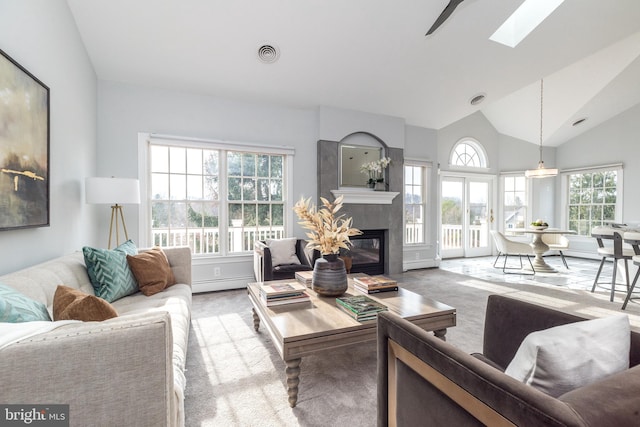 carpeted living room with a baseboard heating unit, lofted ceiling with skylight, and a tile fireplace