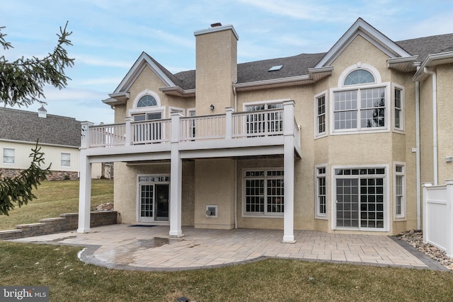 rear view of property with a lawn, a balcony, and a patio