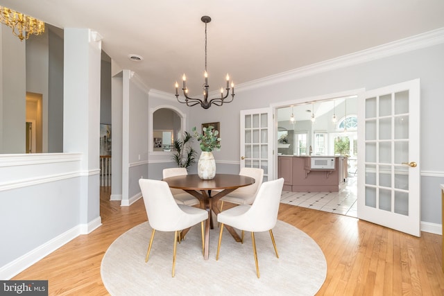 dining space featuring crown molding, wood-type flooring, and a notable chandelier