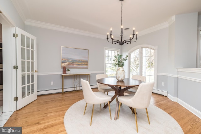 dining room with light wood-type flooring, a baseboard heating unit, a notable chandelier, and ornamental molding