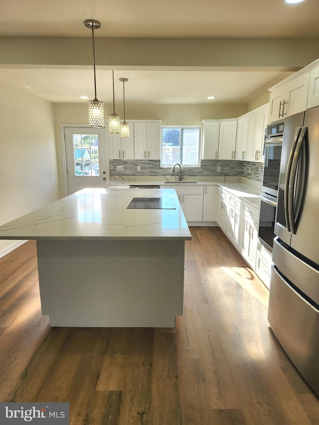 kitchen featuring a center island, white cabinets, sink, decorative backsplash, and appliances with stainless steel finishes