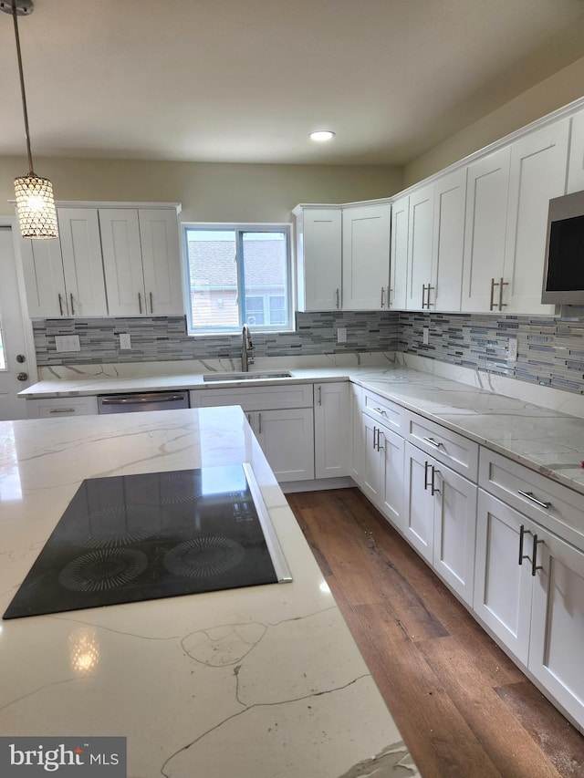 kitchen featuring light stone countertops, appliances with stainless steel finishes, sink, decorative light fixtures, and white cabinetry