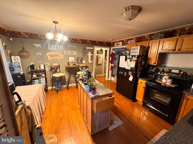 kitchen with black appliances, pendant lighting, light hardwood / wood-style floors, and a chandelier