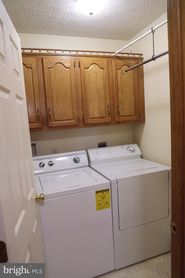 washroom featuring cabinets, independent washer and dryer, and a textured ceiling