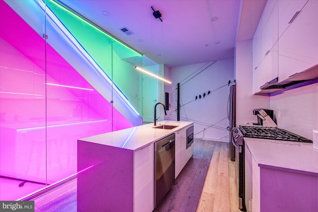 kitchen featuring white cabinets, appliances with stainless steel finishes, a kitchen island with sink, and sink