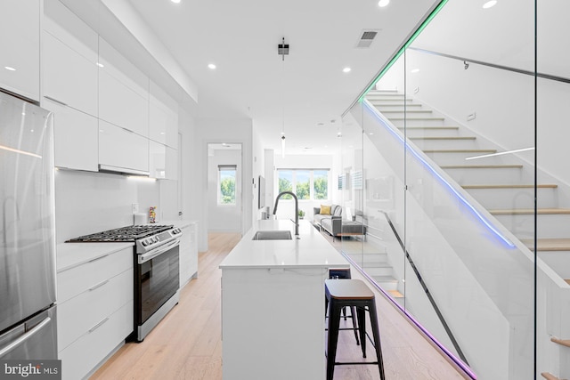 kitchen featuring white cabinetry, a center island, sink, stainless steel appliances, and a kitchen bar