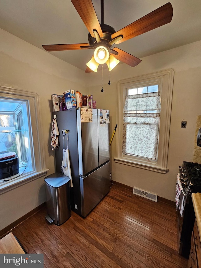 kitchen with dark hardwood / wood-style flooring, stainless steel fridge, black gas stove, and ceiling fan