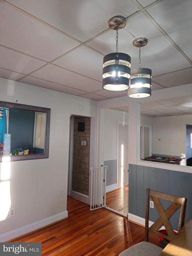 unfurnished dining area featuring a paneled ceiling and hardwood / wood-style flooring