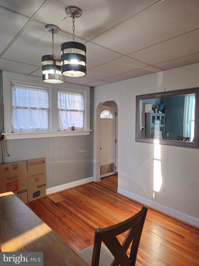 unfurnished dining area with hardwood / wood-style flooring and a drop ceiling