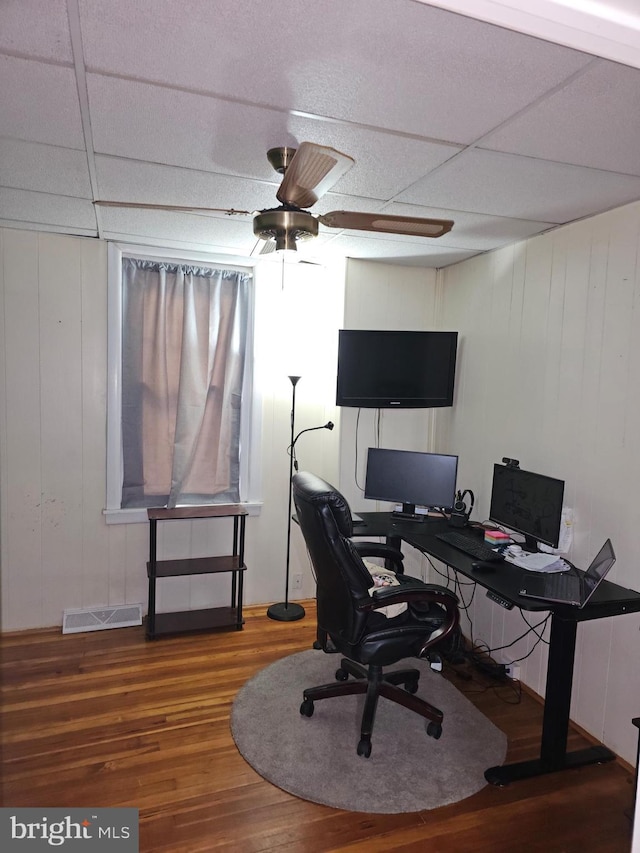 office space with ceiling fan, a drop ceiling, and wood-type flooring