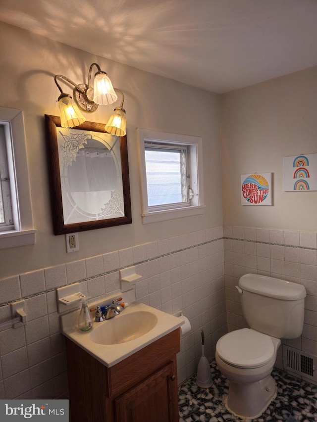 bathroom featuring vanity, toilet, and tile walls