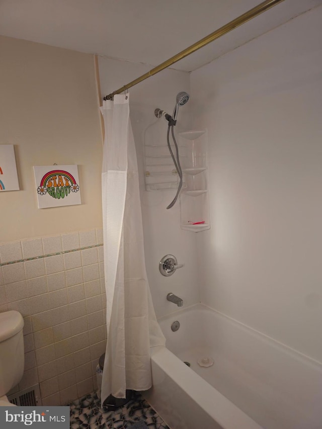 bathroom featuring toilet, tile walls, and shower / tub combo with curtain