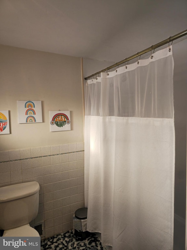 bathroom featuring toilet and tile walls