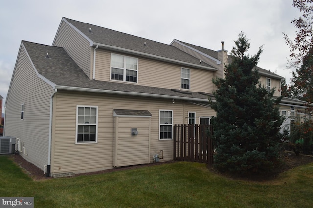 back of property with central air condition unit and a yard