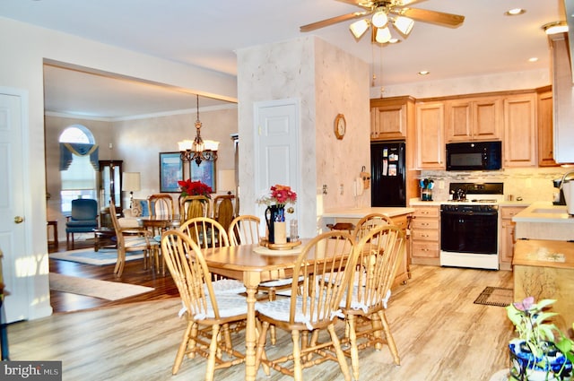 dining space with sink, ornamental molding, ceiling fan with notable chandelier, and light wood-type flooring