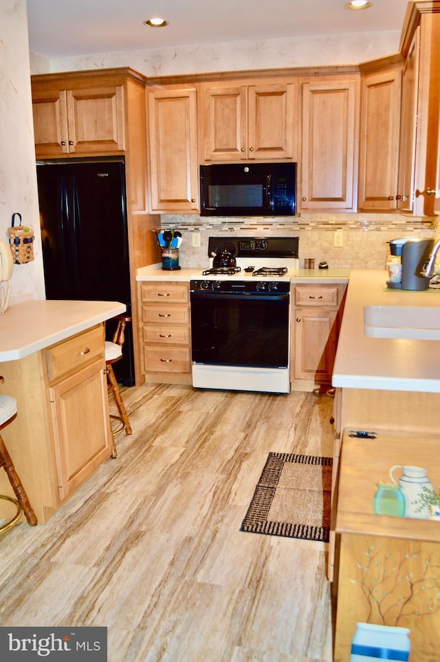 kitchen featuring a kitchen breakfast bar, tasteful backsplash, sink, and black appliances